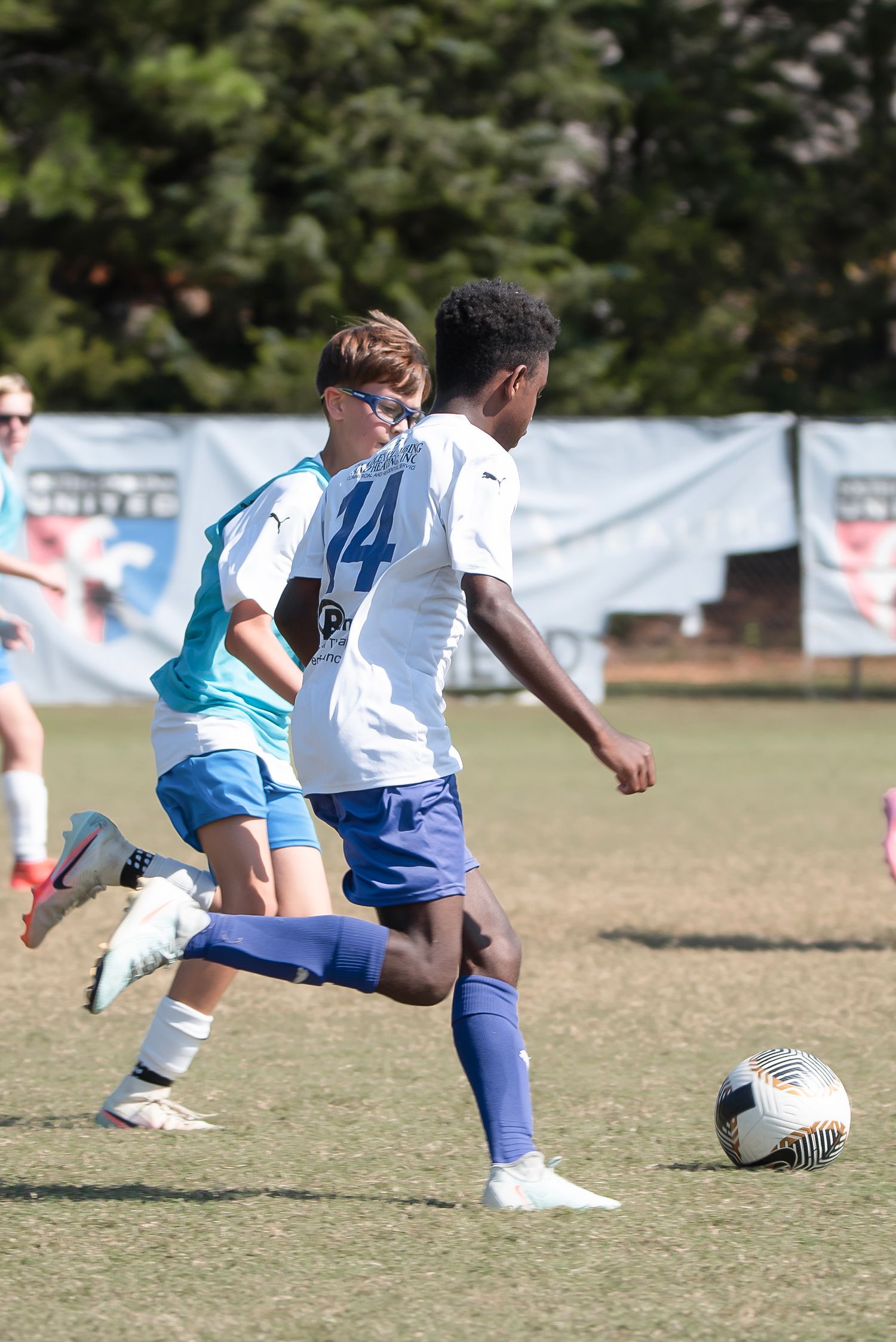 Youth soccer players compete for the ball during an outdoor match on a grass field.