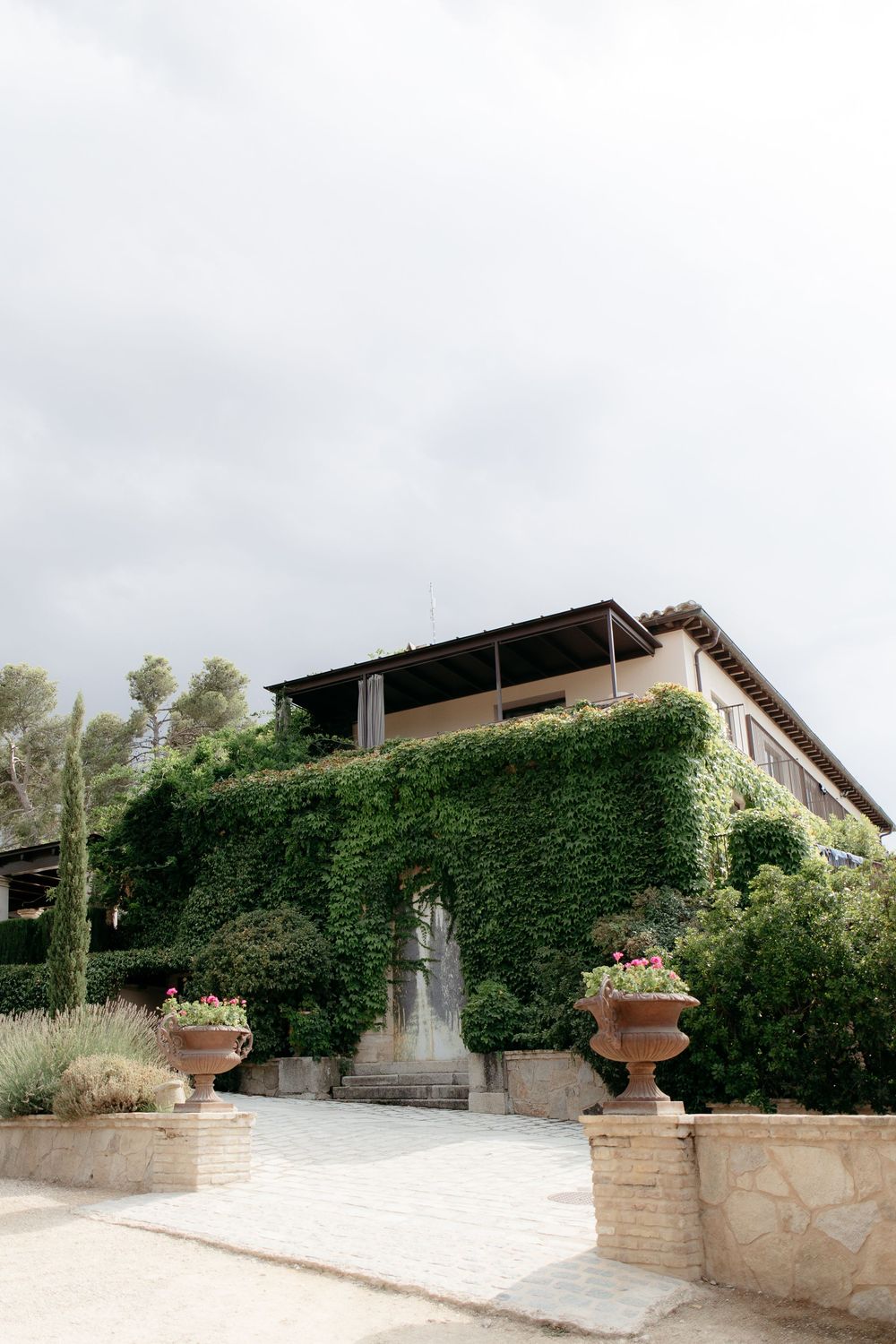 Modern stone villa with ivy-covered walls and landscaped terraces set against a sunny Mediterranean backdrop.
