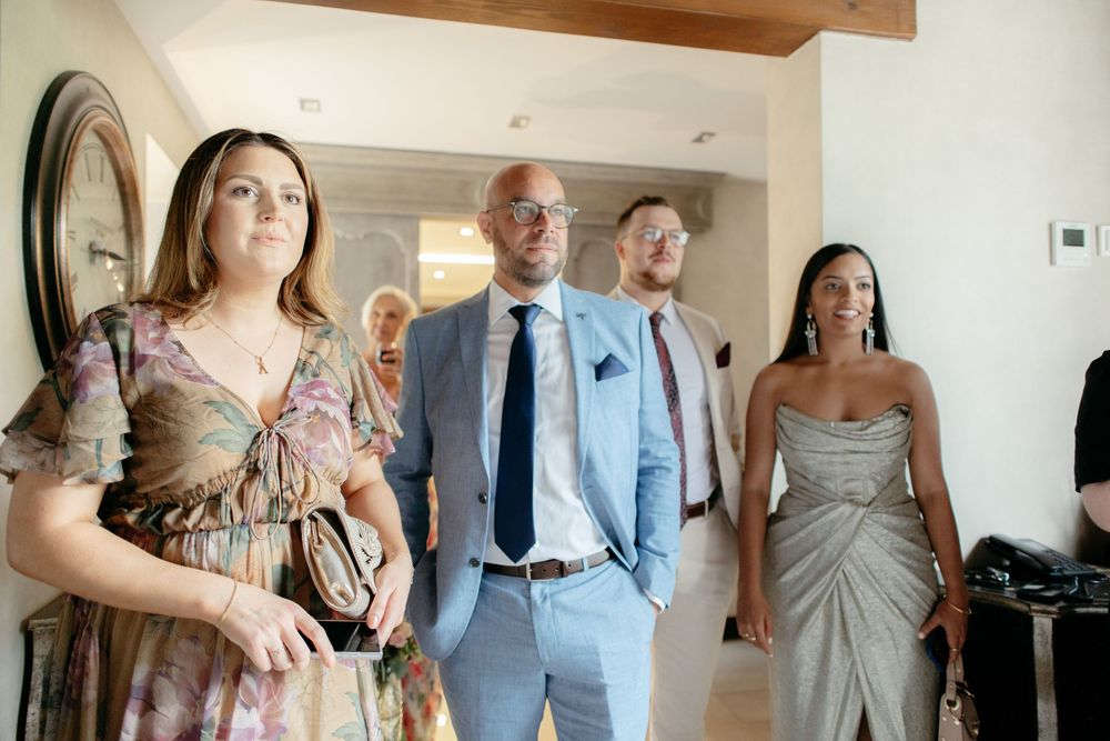A group of wedding attendees walk together in formal attire through an indoor venue.