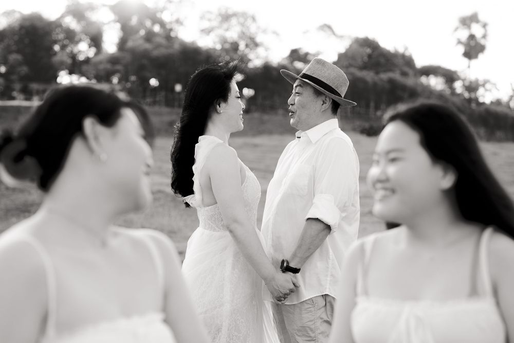 Black and white photo of people in white outfits laughing together outdoors.