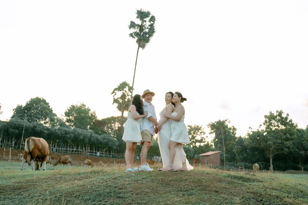 Group in white clothing walking together across a grassy hillside at sunset.