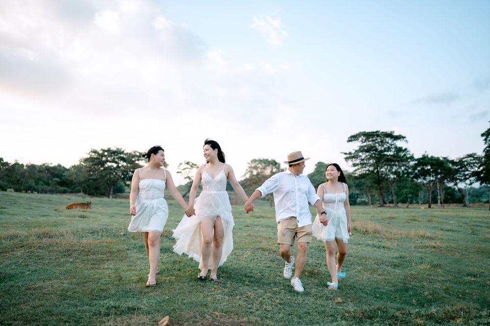 People in white clothing running playfully through a sunny green field.