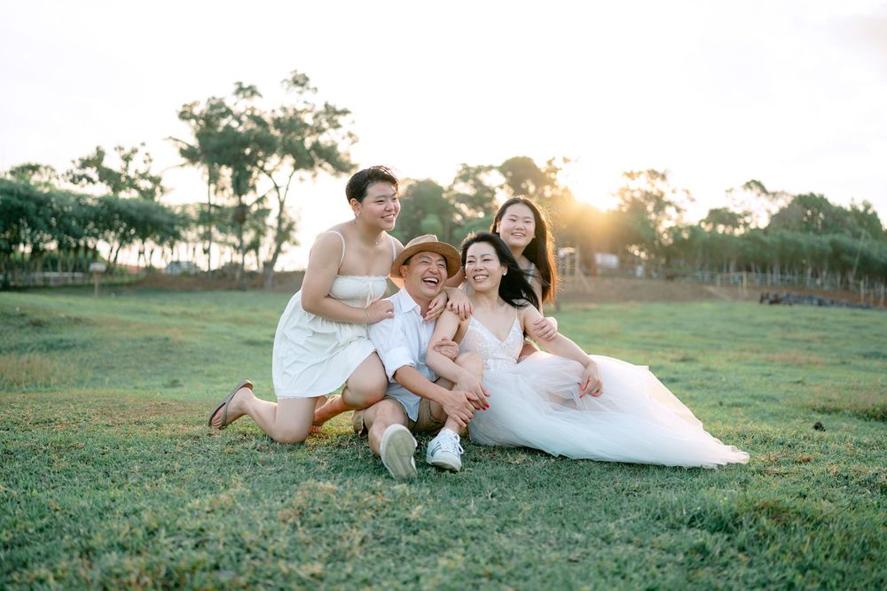 Family group lounging together on grass during golden hour photoshoot.