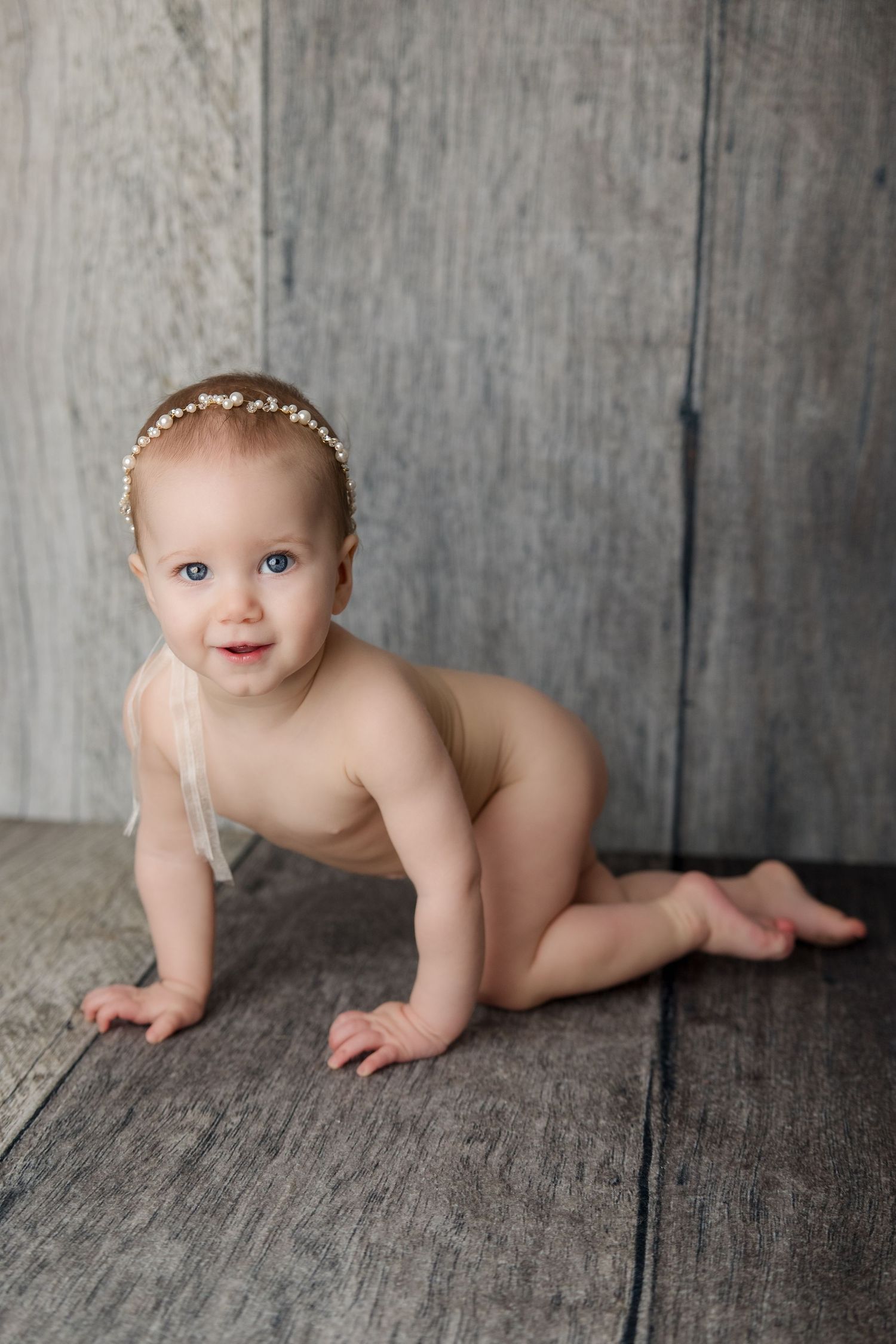 Professional baby photography series showing crawling movements on rustic wooden floor with gray backdrop.