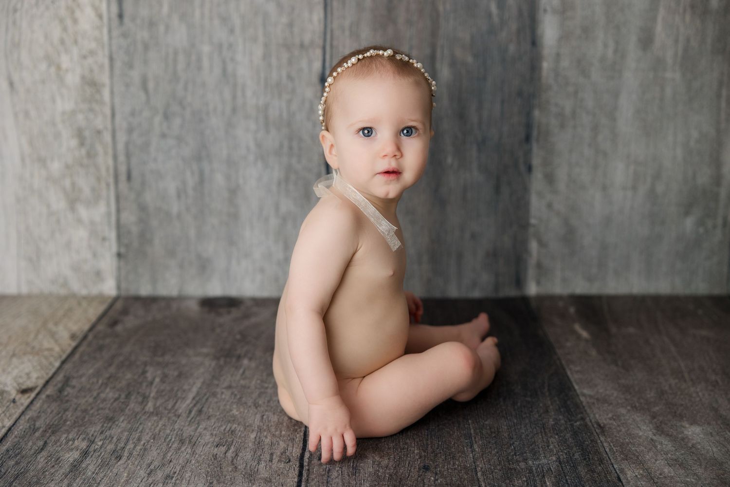 Professional black and white baby photography collage with five adorable poses on rustic wooden floor.