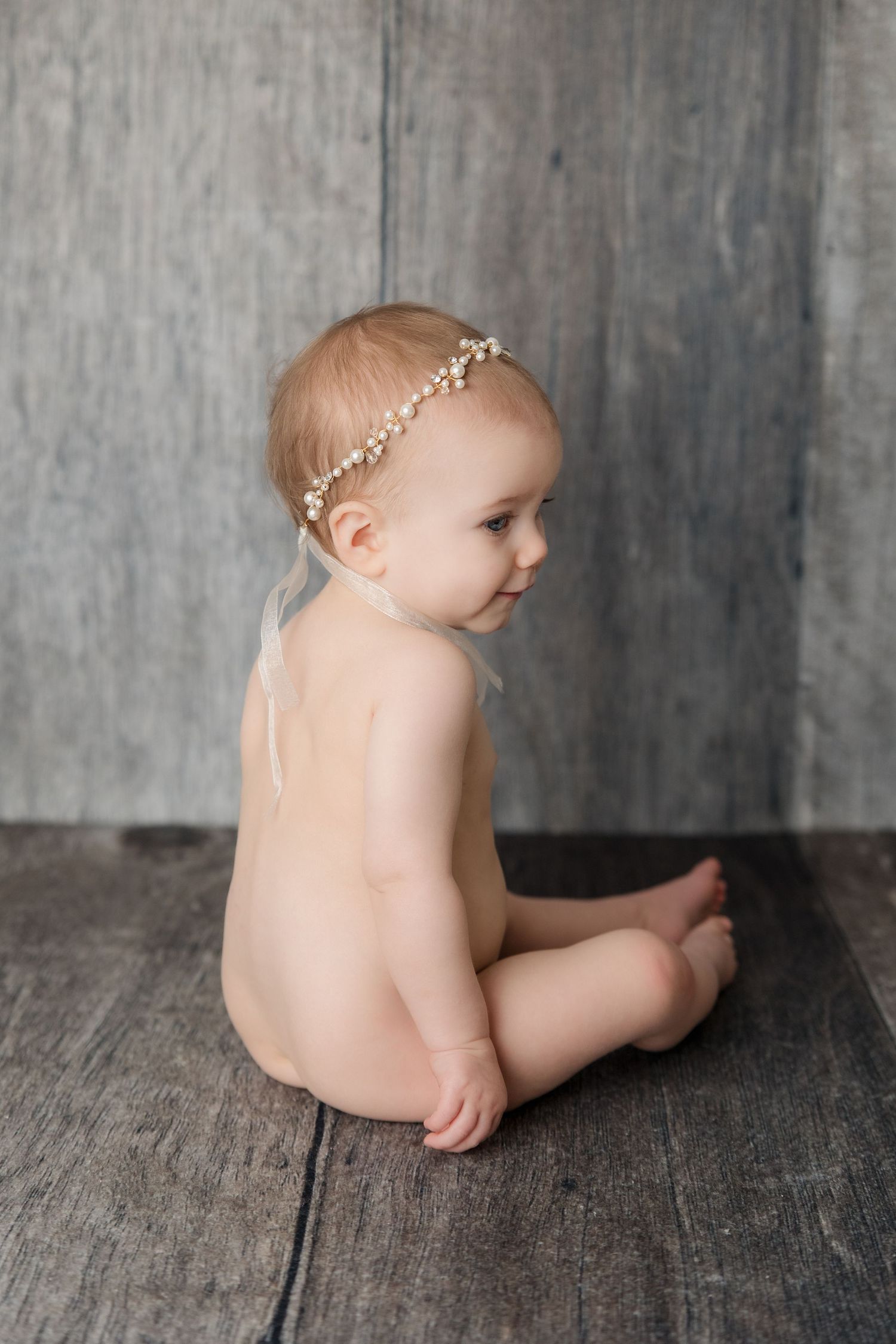 Progressive series of artistic baby photos against a gray textured backdrop showing different poses.