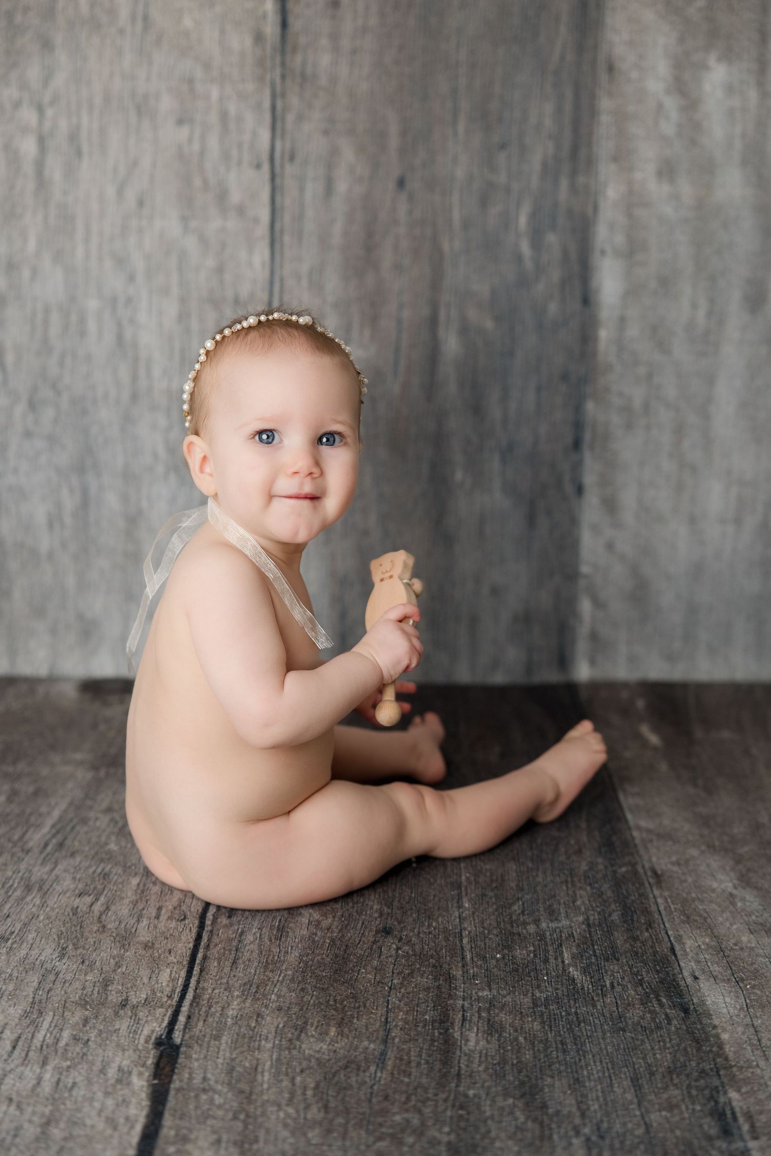 Sweet baby portrait series showing natural sitting poses against weathered gray wooden background.