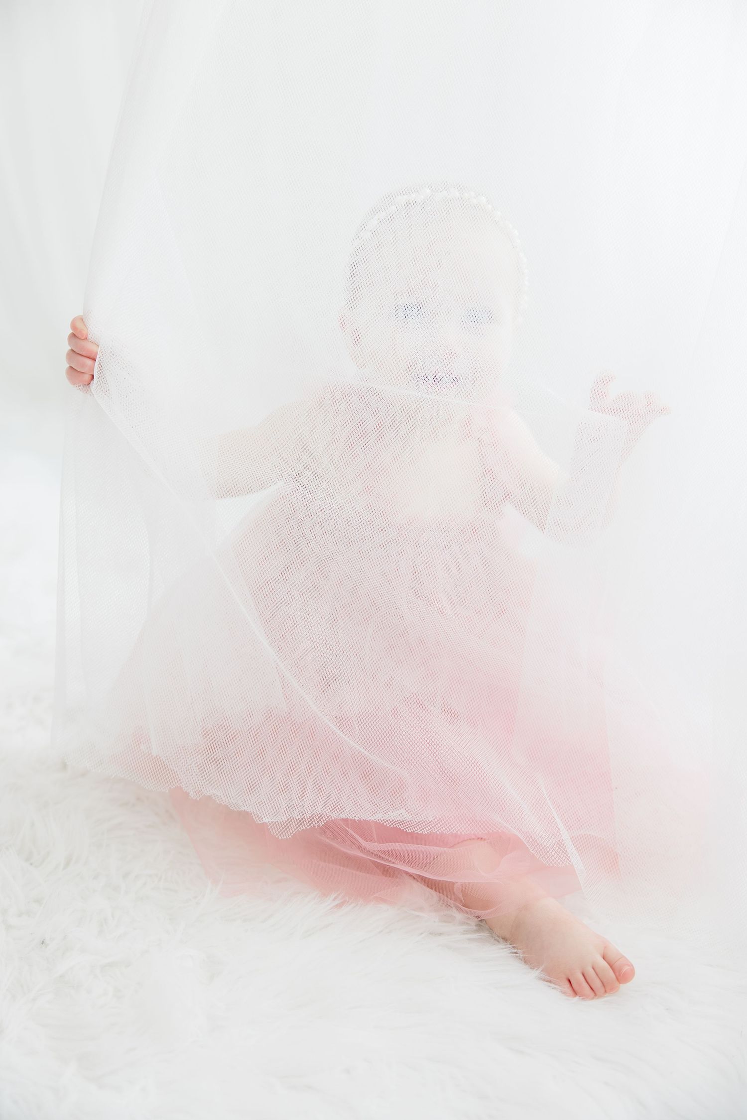 Delicate pink tulle fabric creating a dreamy ethereal effect against a white background.