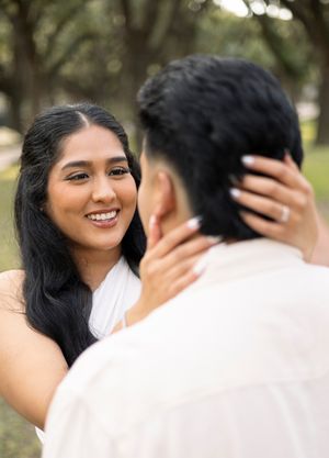 A romantic moment between a couple embracing in a garden setting with soft natural lighting.
