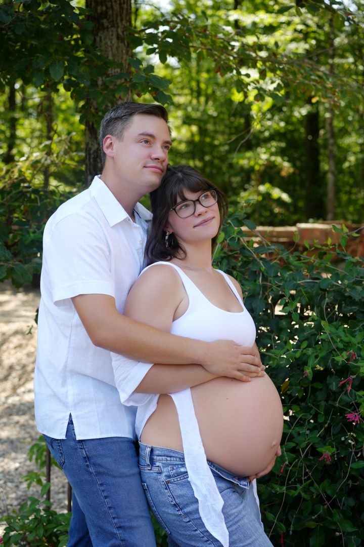 Couple embracing in a garden setting with flowering shrubs and greenery in the background.