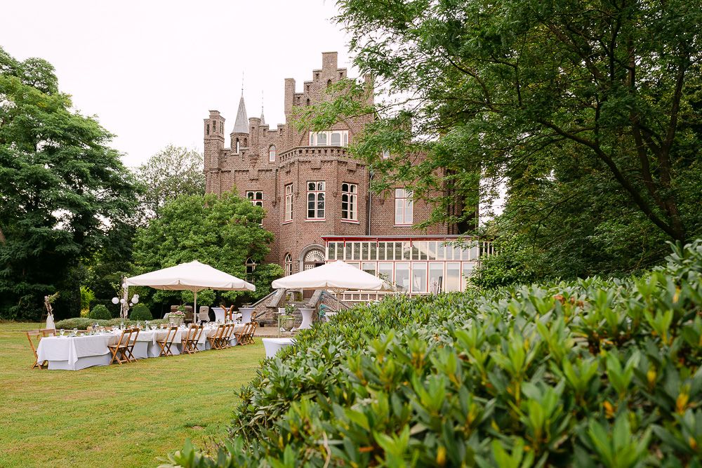 Exterior view of Kasteel Aerwinkel with guests gathering for the wedding reception in the garden.