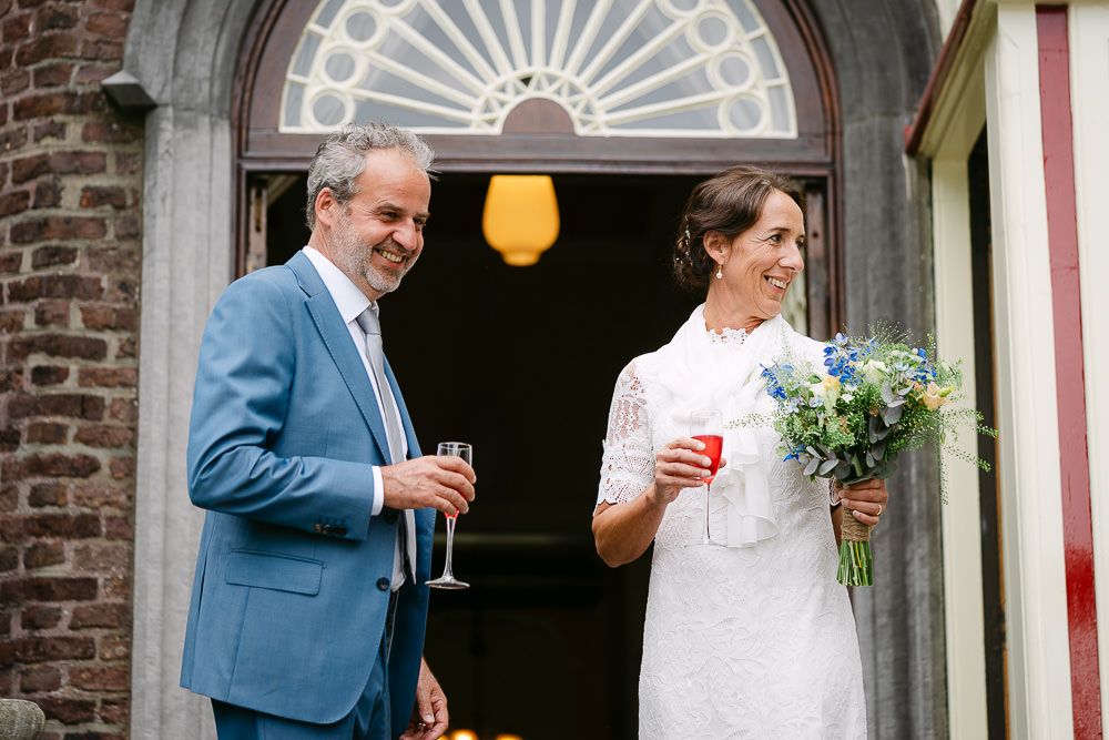 Bride and groom smiling with drinks in hand after their wedding ceremony at Kasteel Aerwinkel.