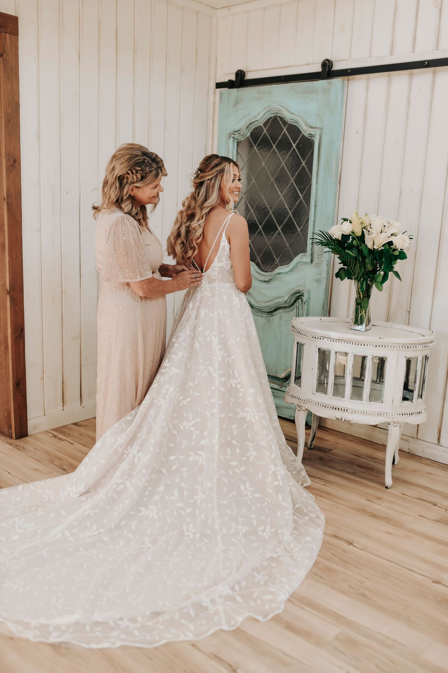 Bride’s mother helping fasten dress in bridal suite