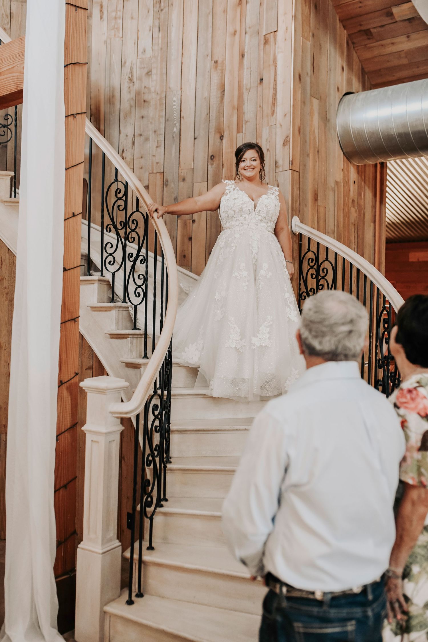 Bride in wedding gown coming down modern barn staircase at Whispering Oaks