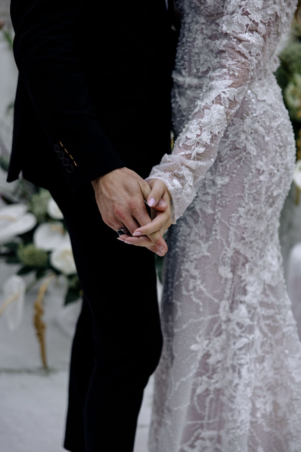 Close-up detail shots of a white lace wedding dress against a black suit during a formal ceremony.