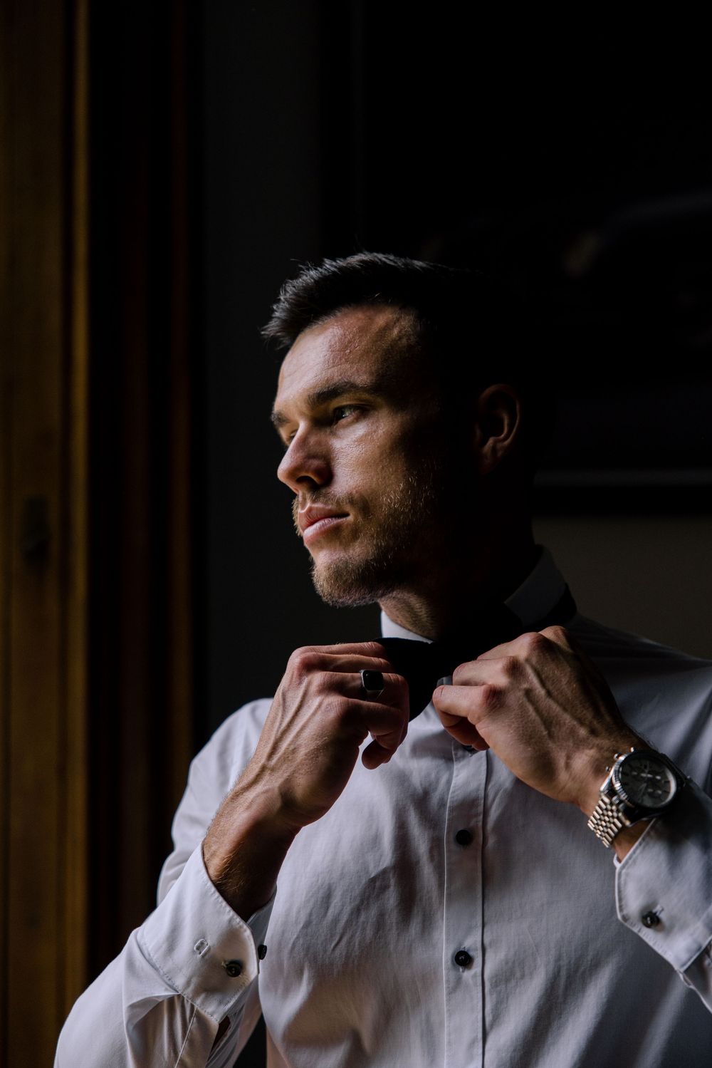 A sequence of shots showing someone adjusting their collar and tie in a dimly lit room.