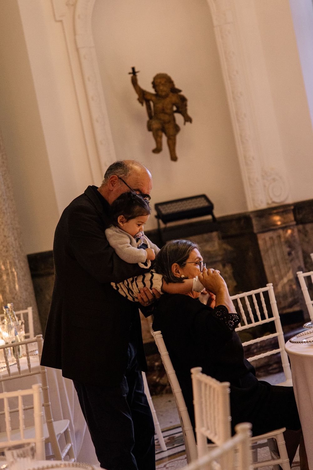 A series of candid photographs showing people interacting in a white-walled room with elegant architectural details.