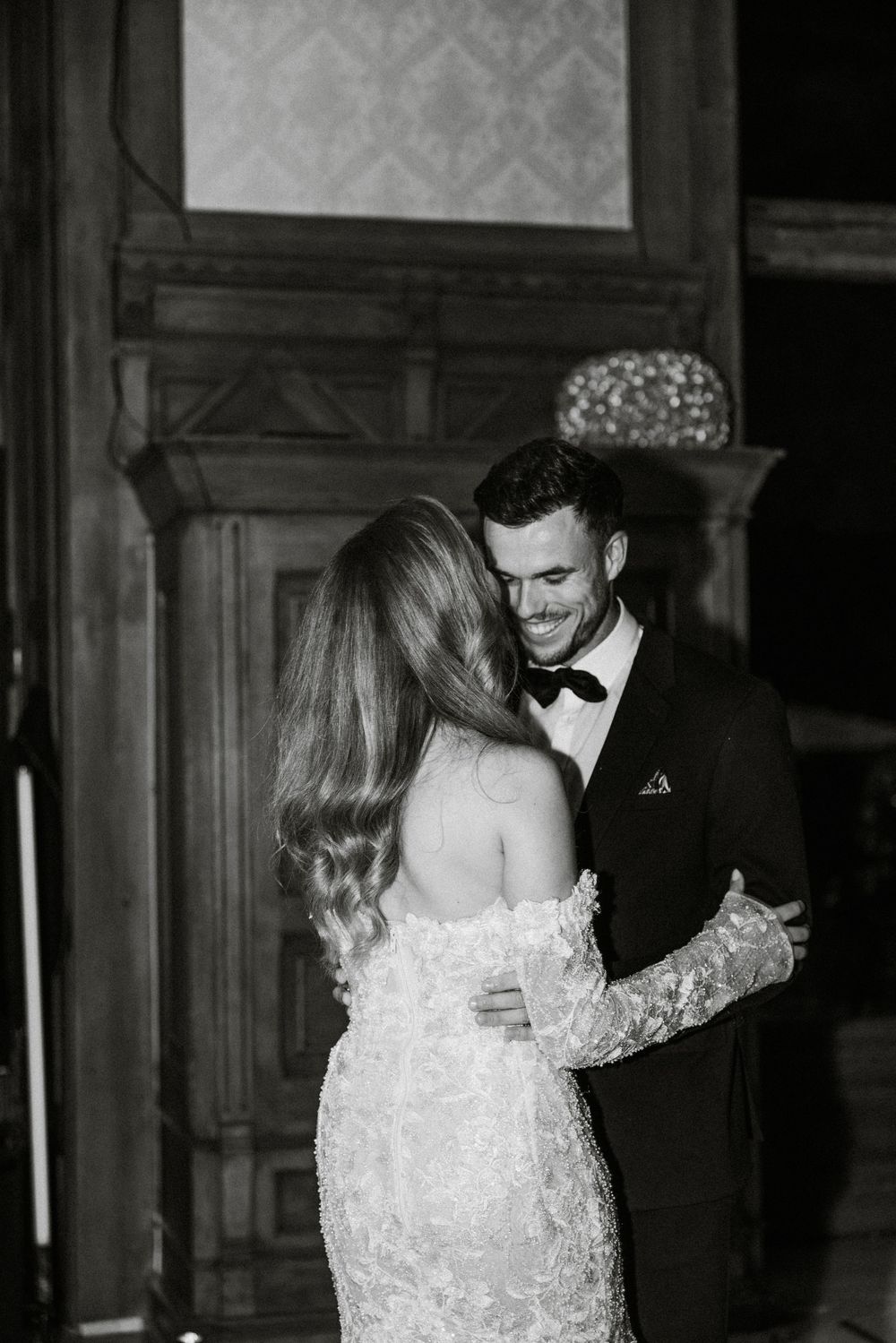 A couple shares a romantic moment in black and white, with the bride wearing a delicate lace wedding dress.