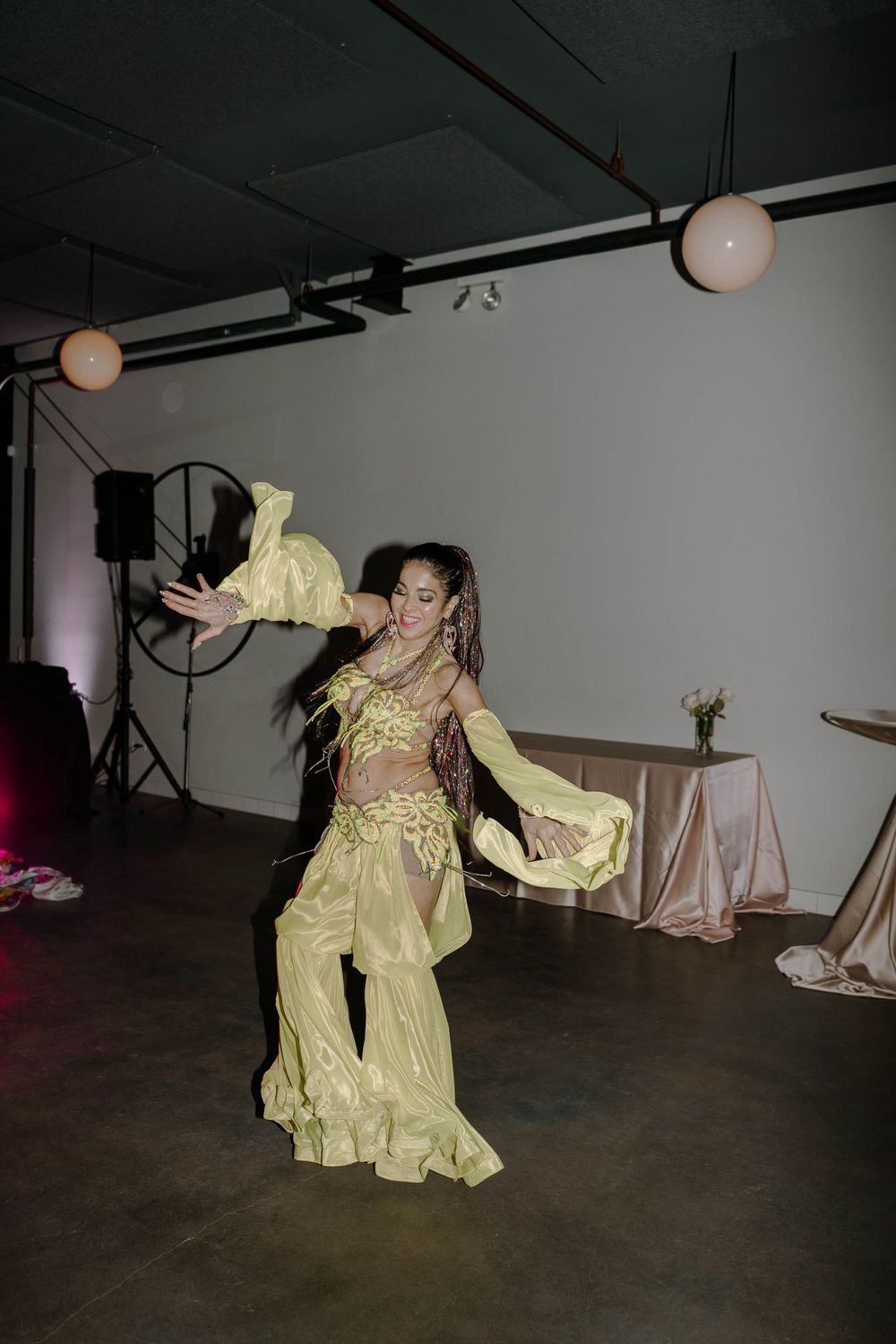 A performance art piece showing dancers in yellow vintage-style dresses moving dramatically in a dark studio space.