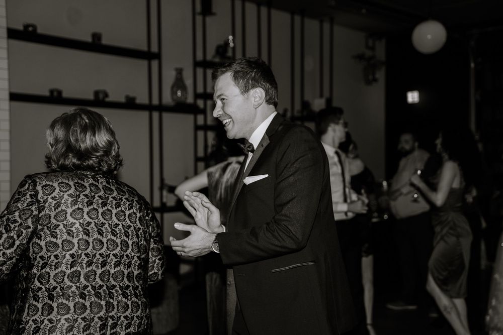 Vintage black and white photograph showing couples dancing at a formal social gathering in an indoor venue.