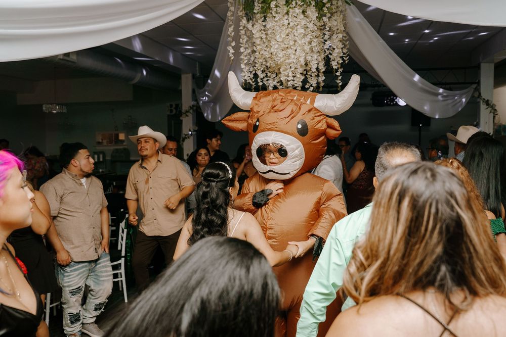 People dancing and celebrating together at a lively wedding reception under a crystal chandelier.