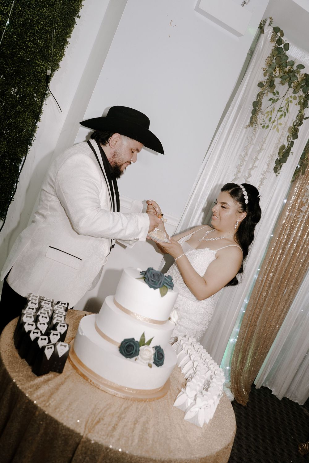 A couple shares a playful moment while cutting their elegant white wedding cake at their reception.