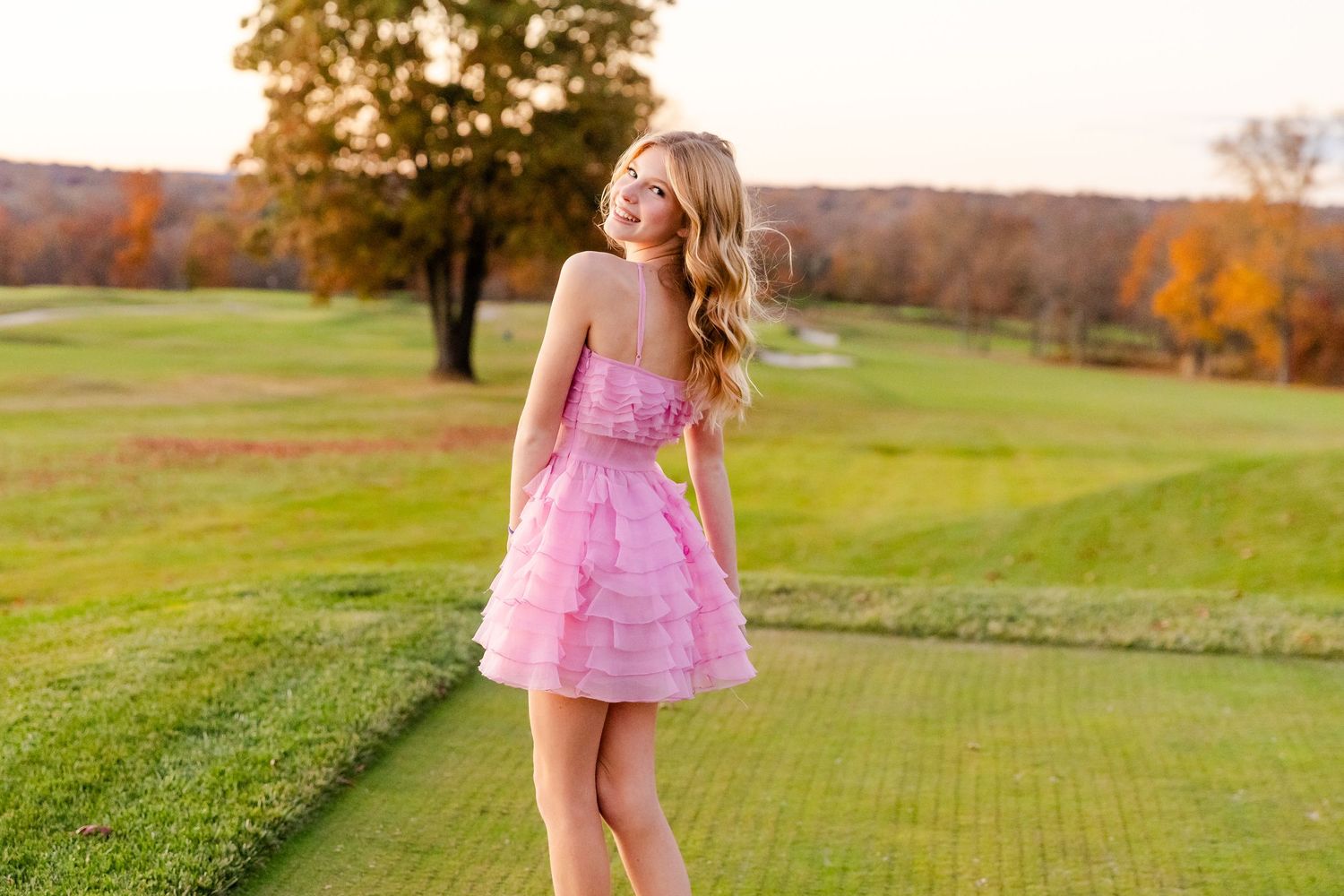 A pink dress against a backdrop of illuminated stone arches with pink lighting and colorful floral arrangements.