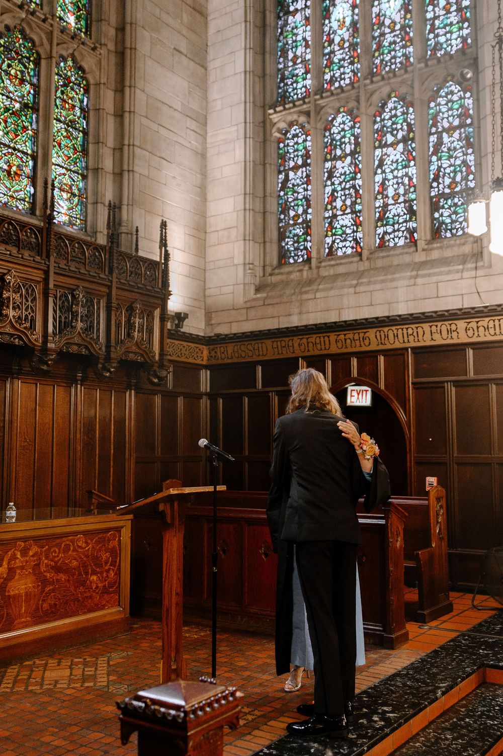 Beautiful chapel interior with wood paneling and stained glass windows during a wedding ceremony.