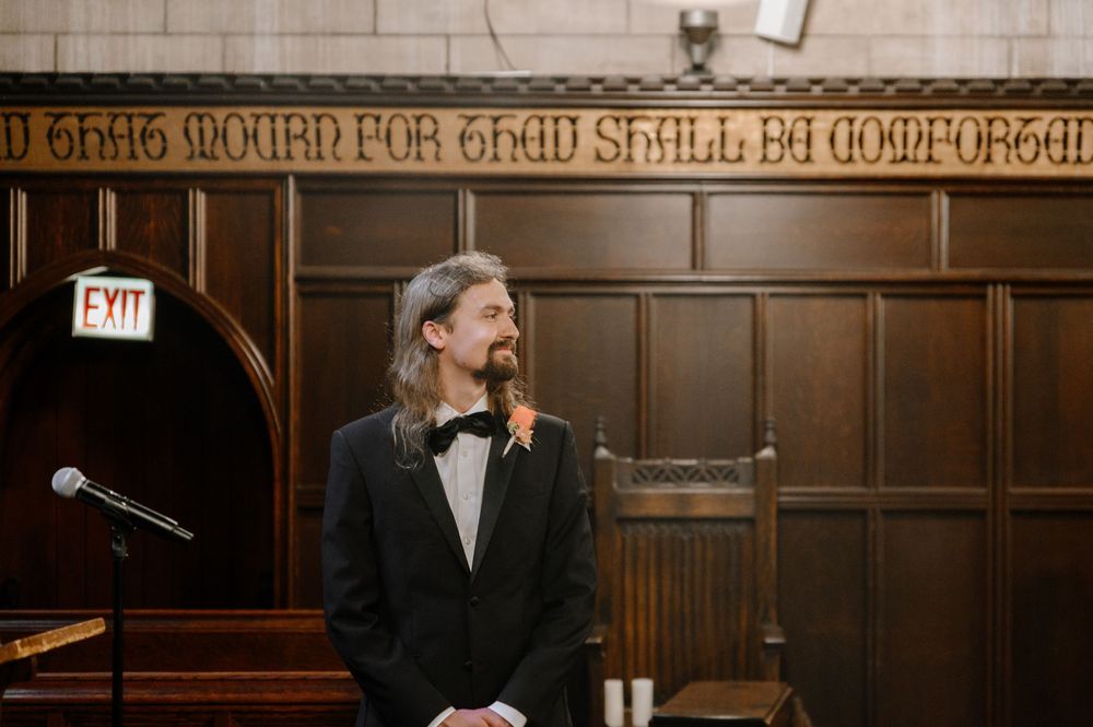 Gothic-style great hall with ornate wood paneling and decorative text inscription along the wall.