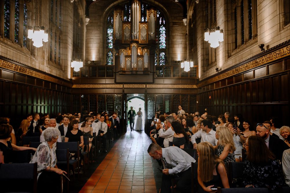 Wide view of a church wedding ceremony showing guests seated in wooden pews under vaulted ceilings.