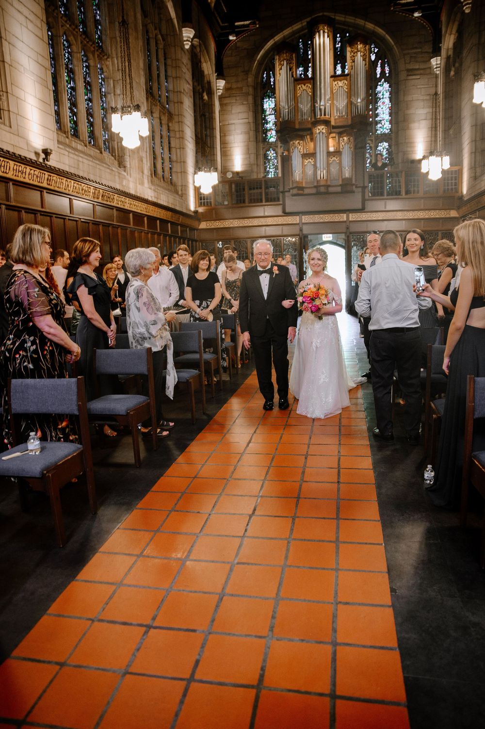 Wedding ceremony in a church with vintage orange tile floors and wooden pews.