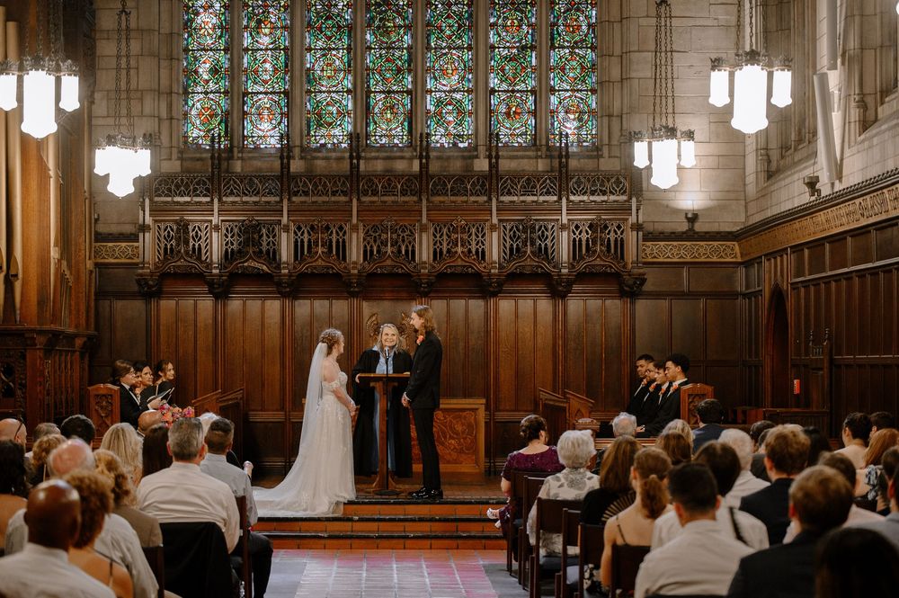 Wide angle view of a grand church wedding ceremony with ornate stained glass windows and Gothic architecture.