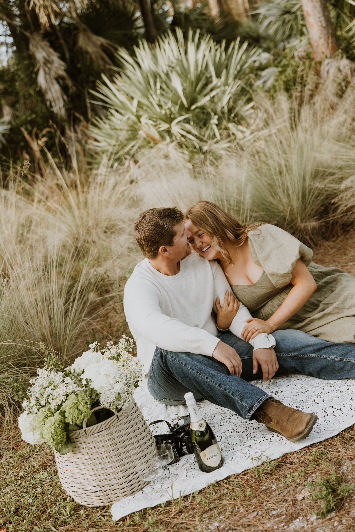 Engagement photos featuring film cameras, picnic, and flowers in woods, nature trail West Palm Beach captured by Lindsay McDow Photography