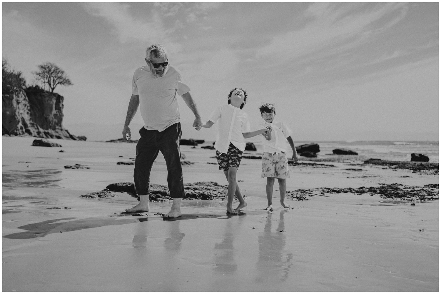 People holding hands while walking together on a wet beach in monochrome.