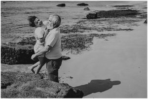Playful beach moment captured in black and white with dramatic shadows on the sand.