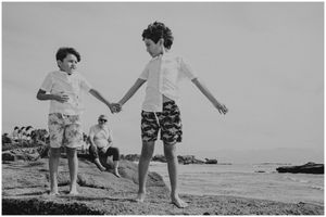 Two people walking together on a rocky beach in black and white photography.