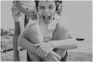 A candid black and white photo showing playful emotion at the beach.
