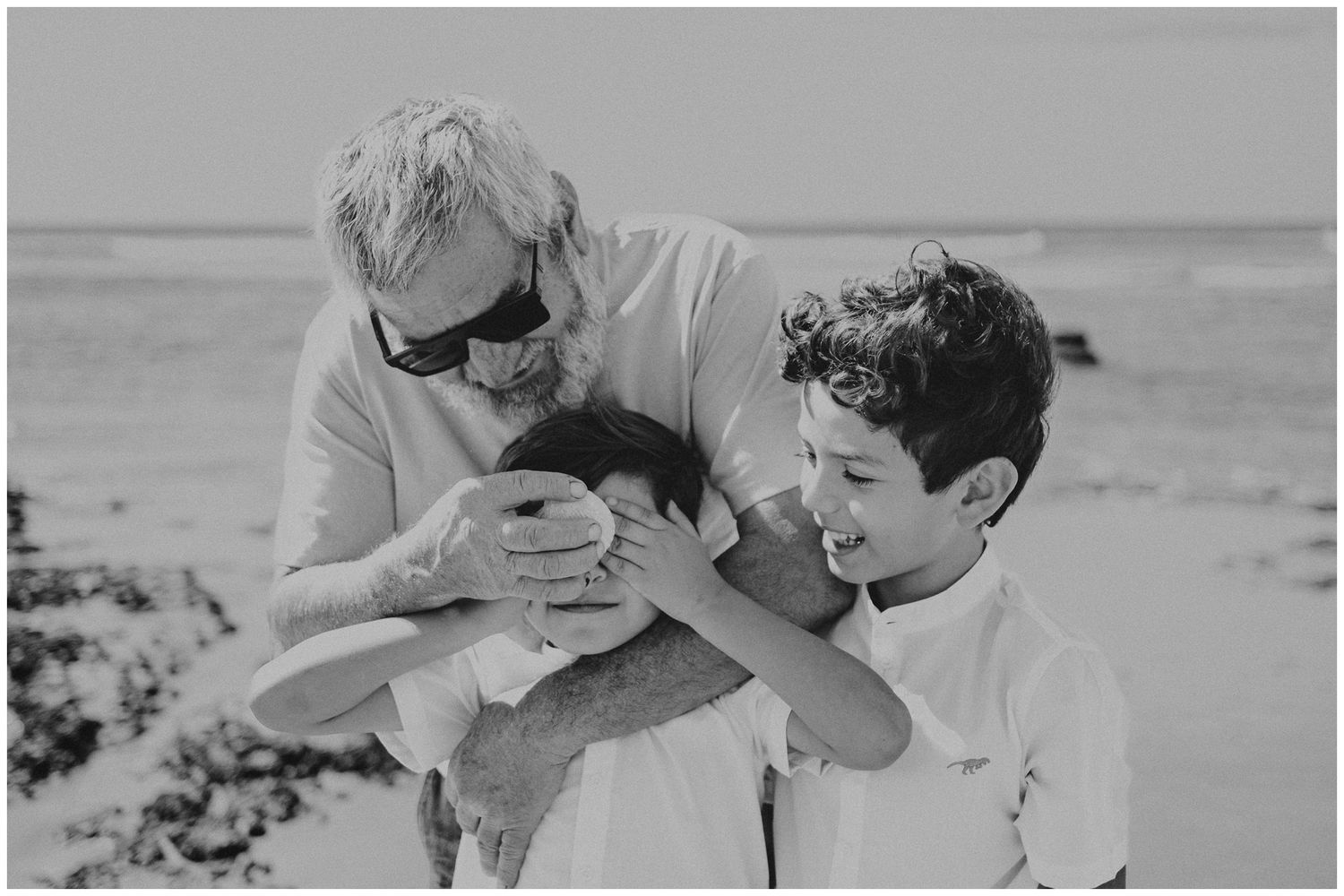 A touching moment between two people on the beach in black and white.