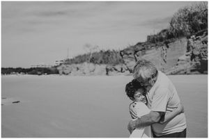 A tender embrace captured on a sandy beach in black and white.