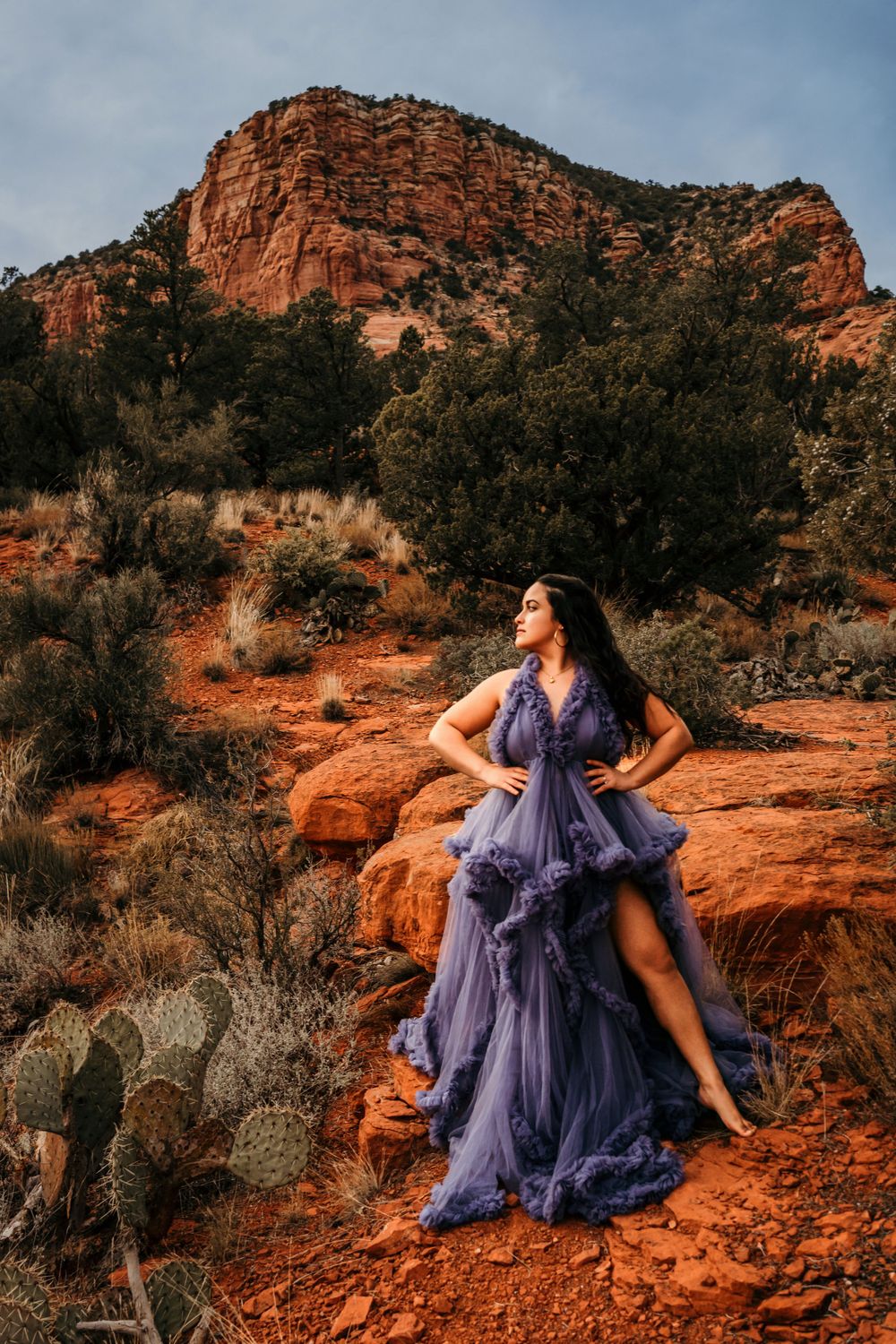 Flowing purple gown creates dramatic silhouette against Sedona's iconic red rock cliffs.