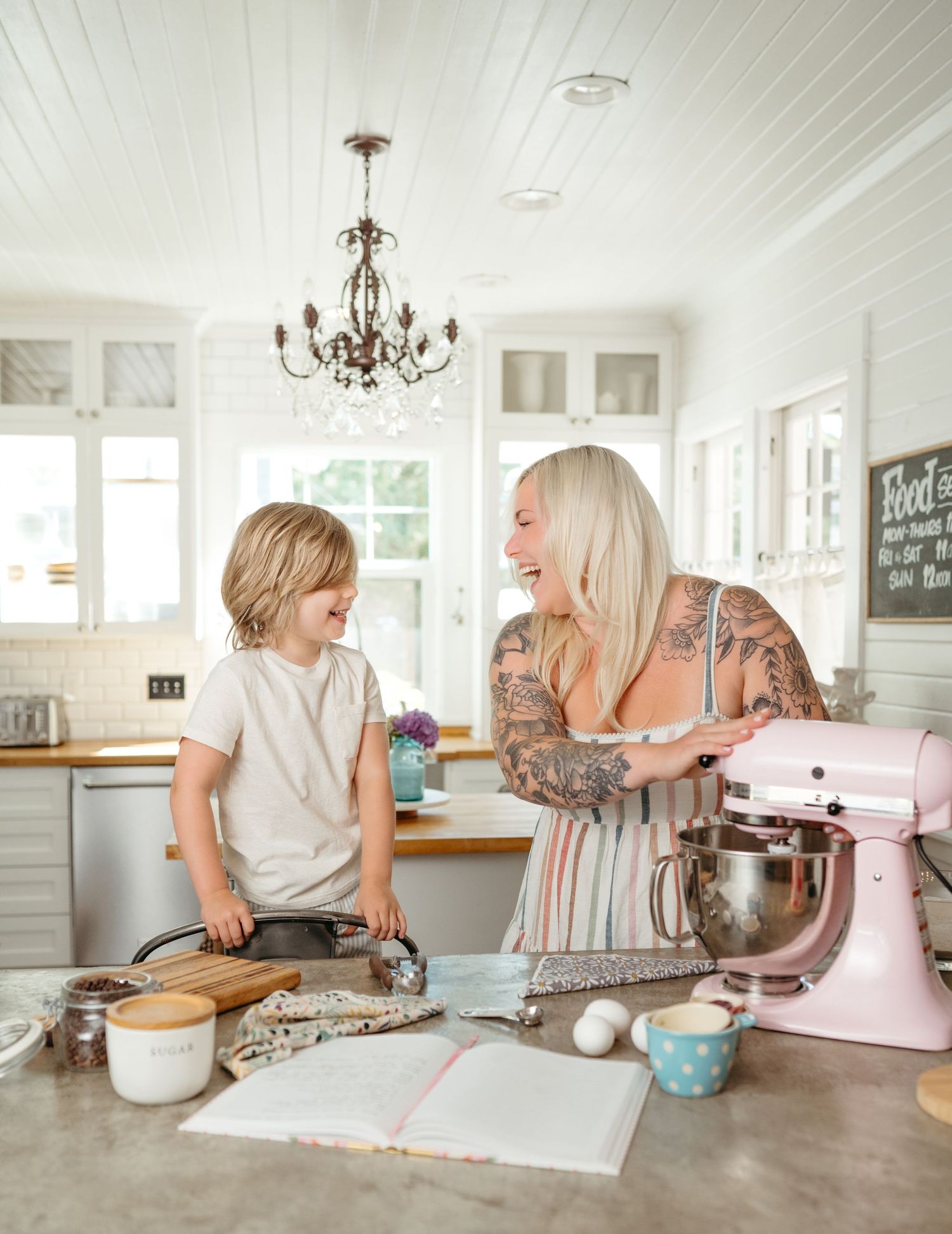 A bright kitchen scene with a mixer and baking ingredients on a marble countertop.