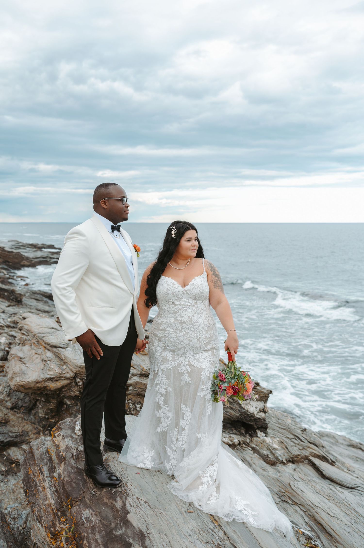 A couple walks down the aisle at their outdoor lakeside wedding ceremony surrounded by guests.