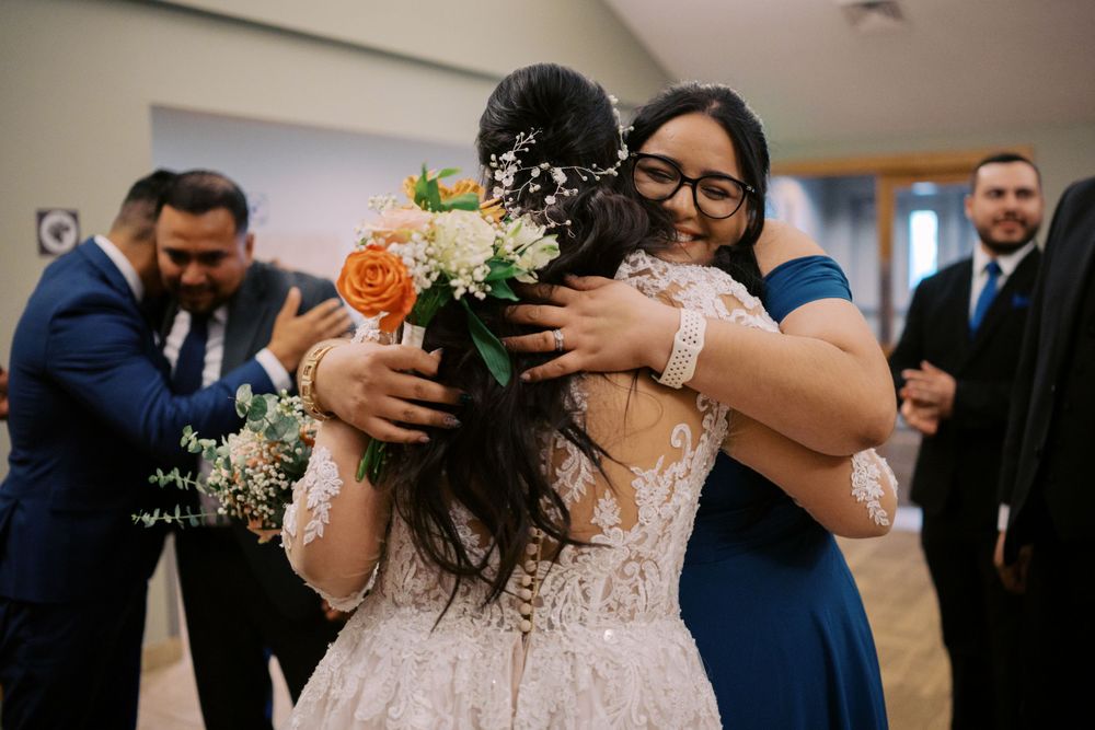 Wedding celebration moment with a joyful embrace and floral bouquet in an indoor venue.