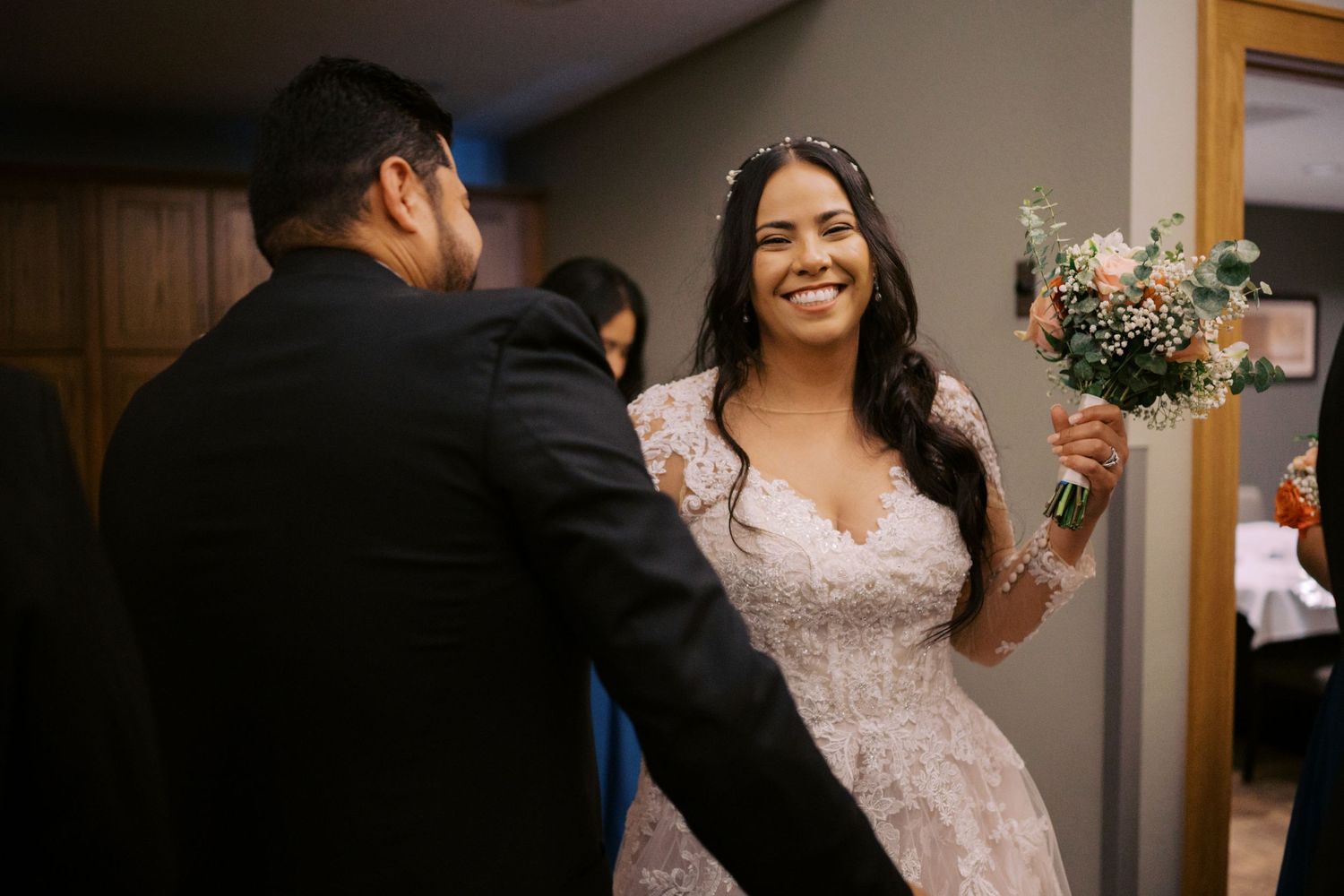 Candid moment of bride holding bouquet during indoor wedding celebration.