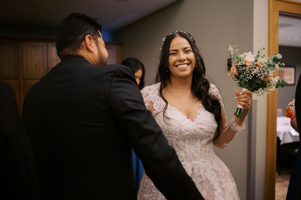 Candid moment of bride holding bouquet during indoor wedding celebration.