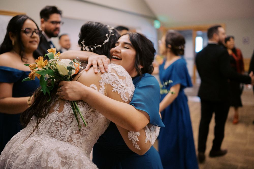 Emotional embrace at a wedding reception with guests in formal attire.