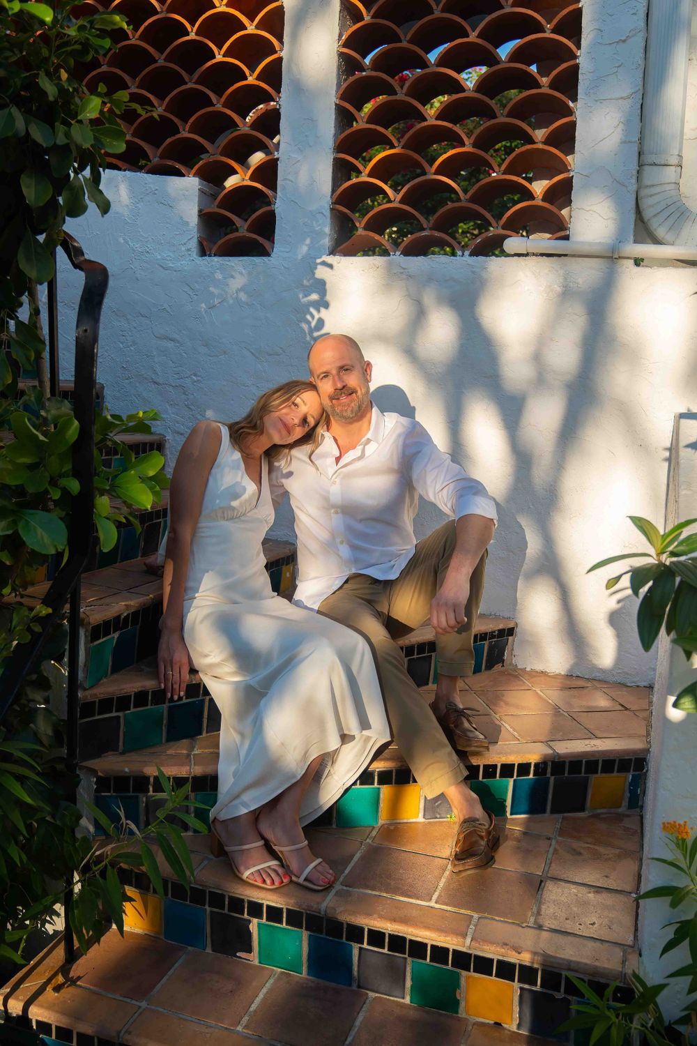Kari and Jeff leaning against one another on multi-colored Mediterranean-style stairs