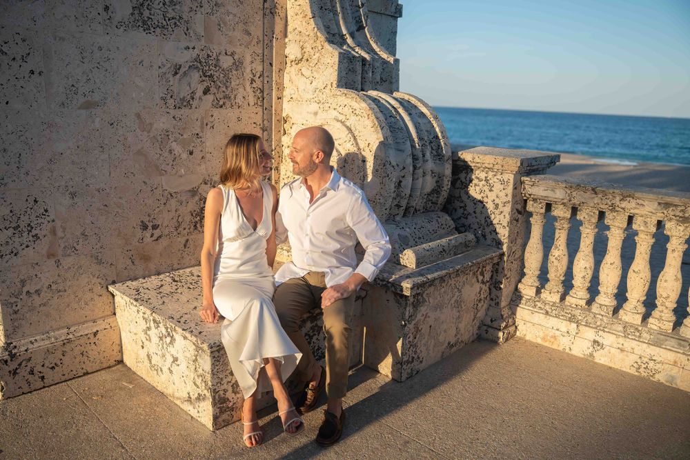 Kari and Jeff looking at each other lovingly while sitting on Worth Ave arch.