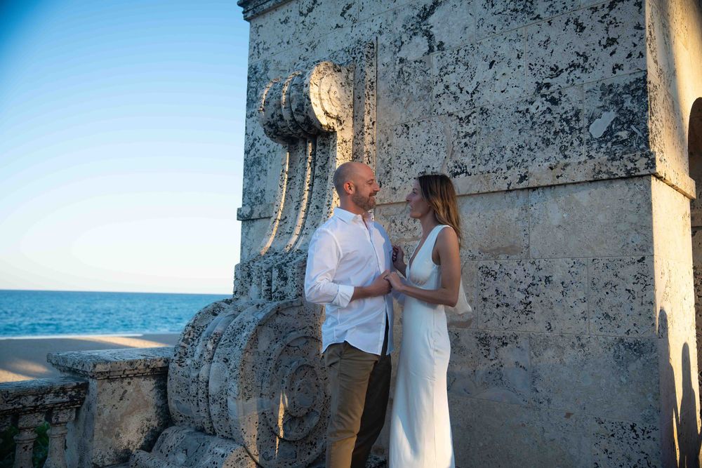 Kari and Jeff holding hands and looking at each other while standing at Worth Ave arch.
