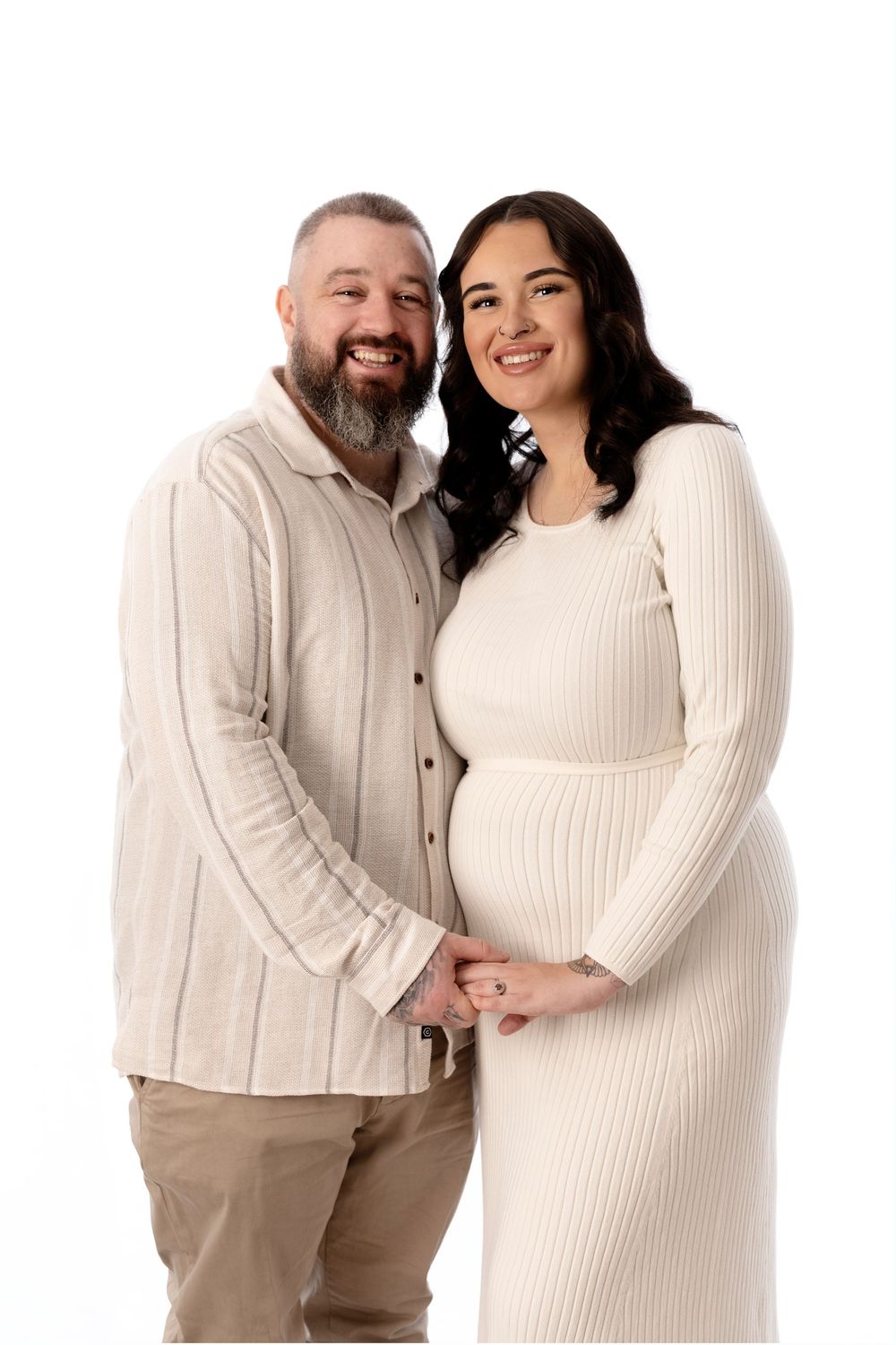 Couple in cream colored outfits posing together for maternity photos.